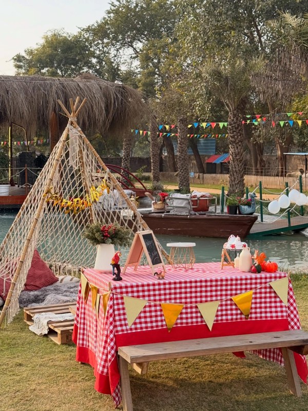 A styled pond-side picnic with teepee and bunting on the lawn