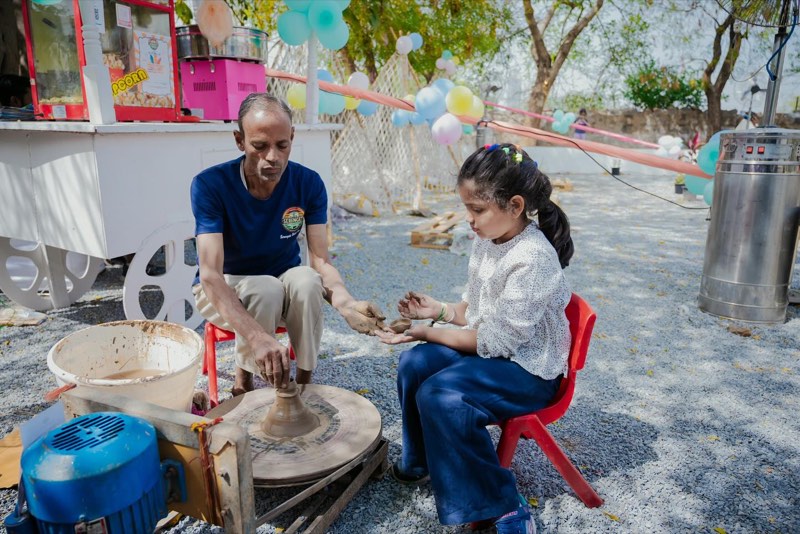 A child learning the pottery wheel with an instructor